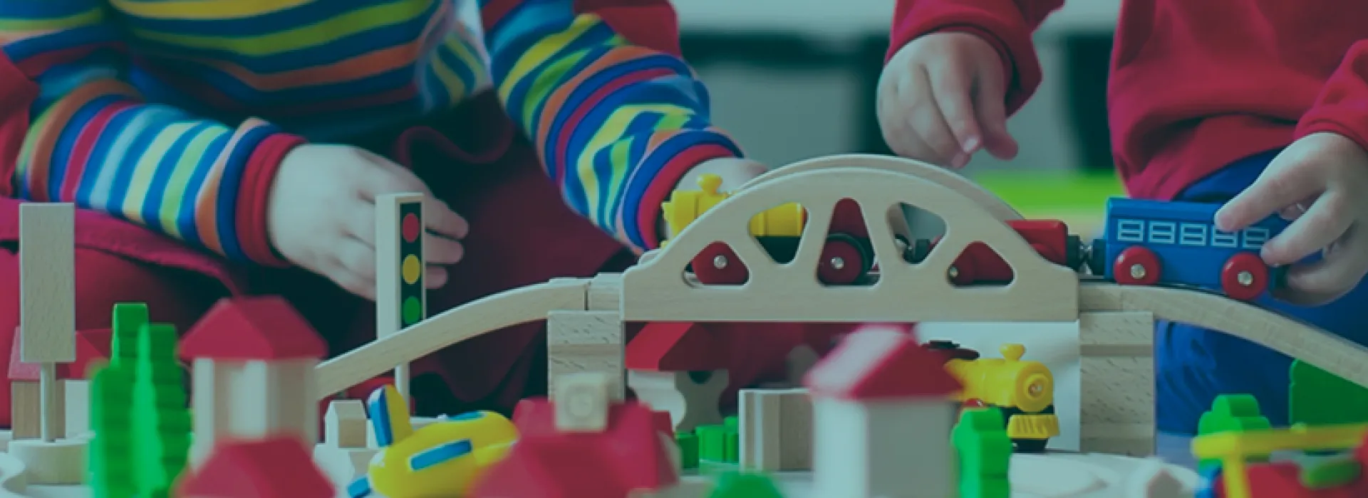 Girl and Boy in Kindergarten class play with a wooden train set