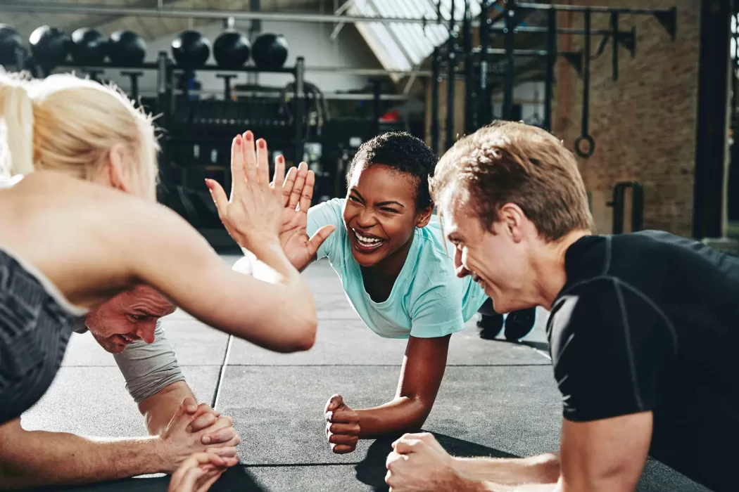 A group of people high fiving eachother while doing push ups together.