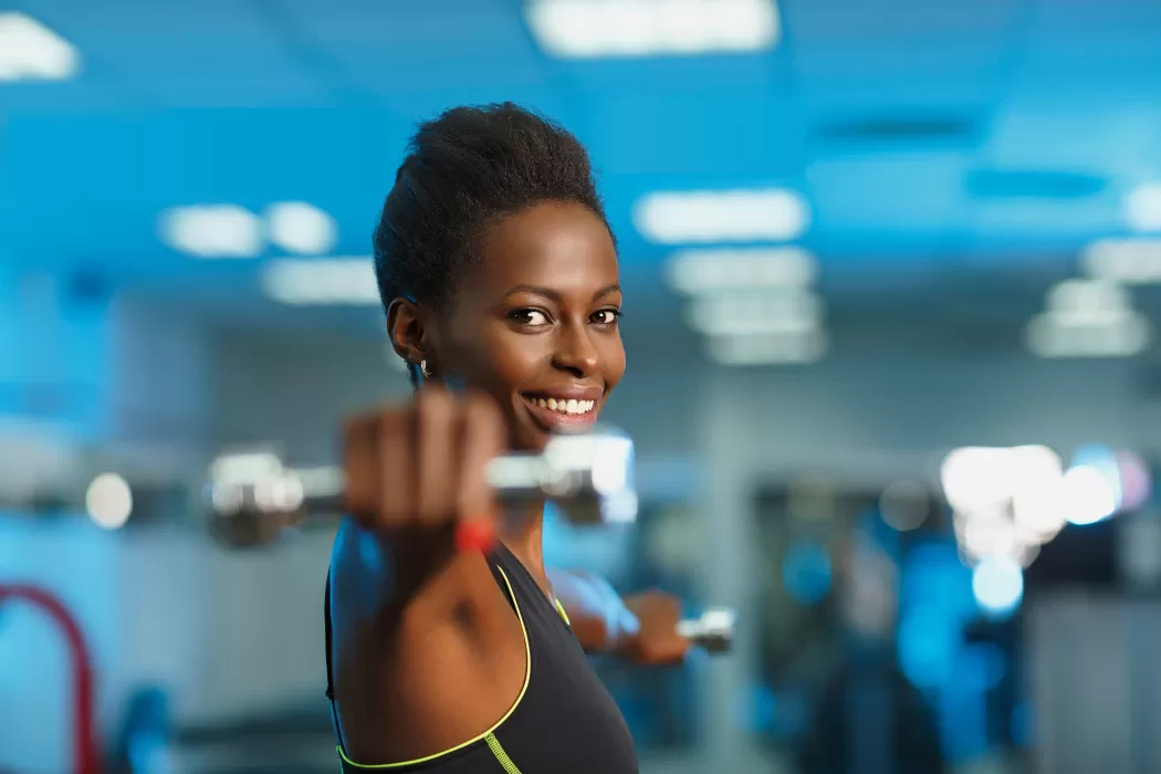 A woman holding weights in the gym smiling