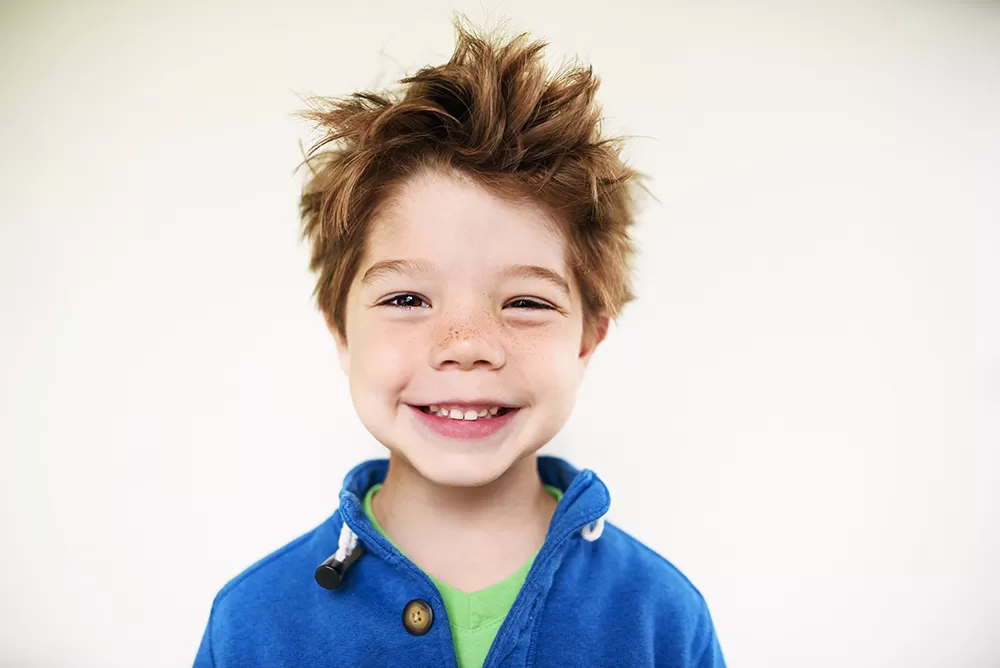 A boy with crazy hair smiling 