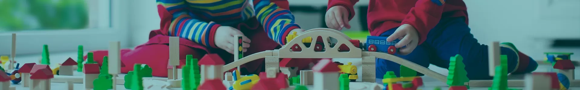 Girl and Boy in Kindergarten class play with a wooden train set