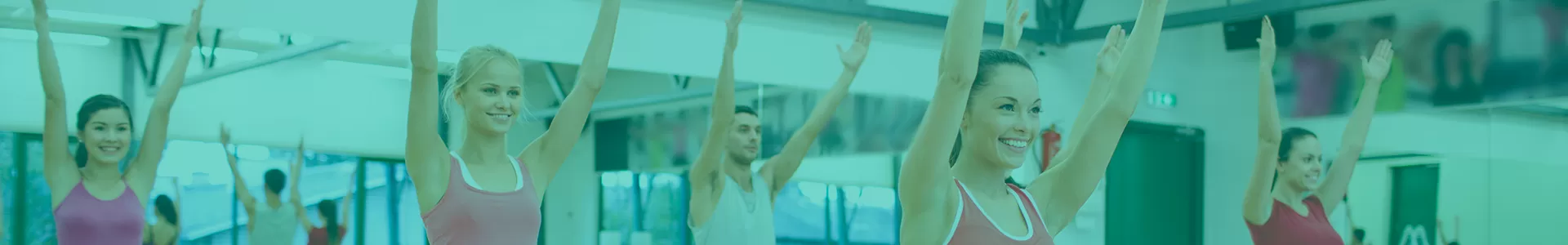 Yoga class with smiling women and one man stretch upwards in a group fitness room with mirror behind them