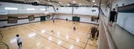 Running track and large gymnasium with teens playing basketball 
