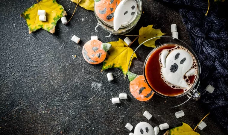A cup of red hot chocolate with ghost marshmallows in it.