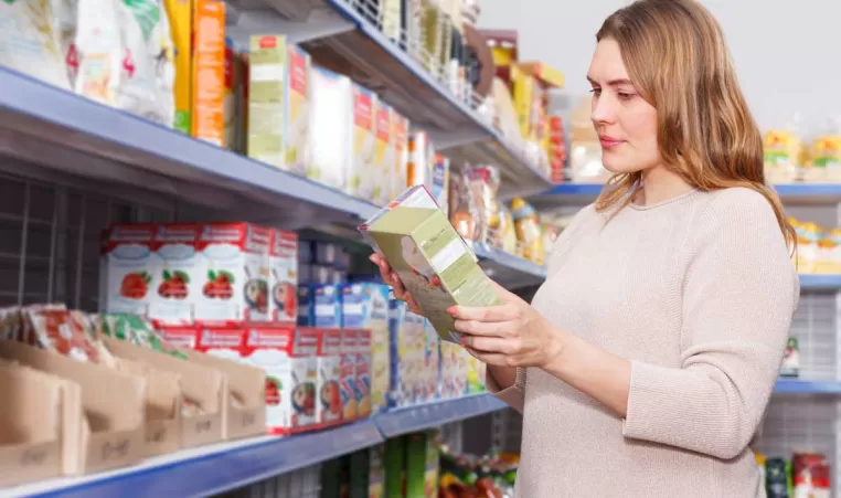 A woman in the grocery looking at non-perishable foods to donate