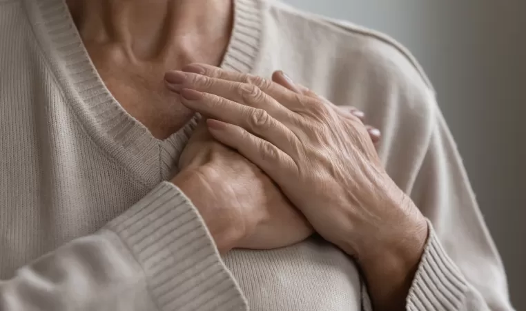 Mature elderly woman feeling heart pain, touching chest with both hands. Thankful senior lady expressing gratitude, love, trust, thanking god, making grateful honor kindness gesture. Close up