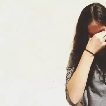 Woman with long brown hair, rubbing her eyes in distress