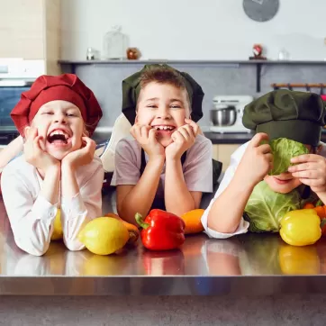 Three kids on kitchen counter laughing.