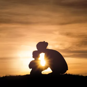 Silhouette of a young mother lovingly kissing her little child