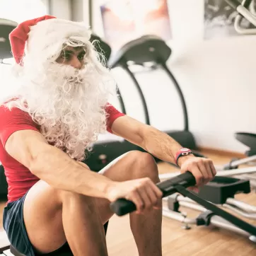 Santa claus training in rowing machine after christmas holidays reducing his fat percentage