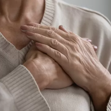 Mature elderly woman feeling heart pain, touching chest with both hands. Thankful senior lady expressing gratitude, love, trust, thanking god, making grateful honor kindness gesture. Close up