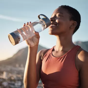 Black woman, runner and drinking water for outdoor exercise, training workout or marathon running recovery. African woman, healthy athlete and hydrate 