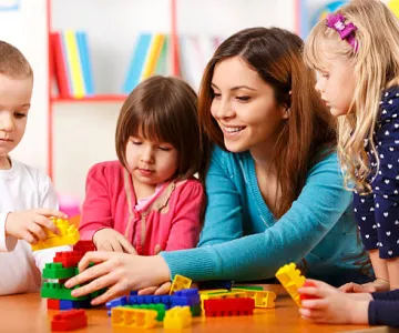 Woman playing blocks with four children