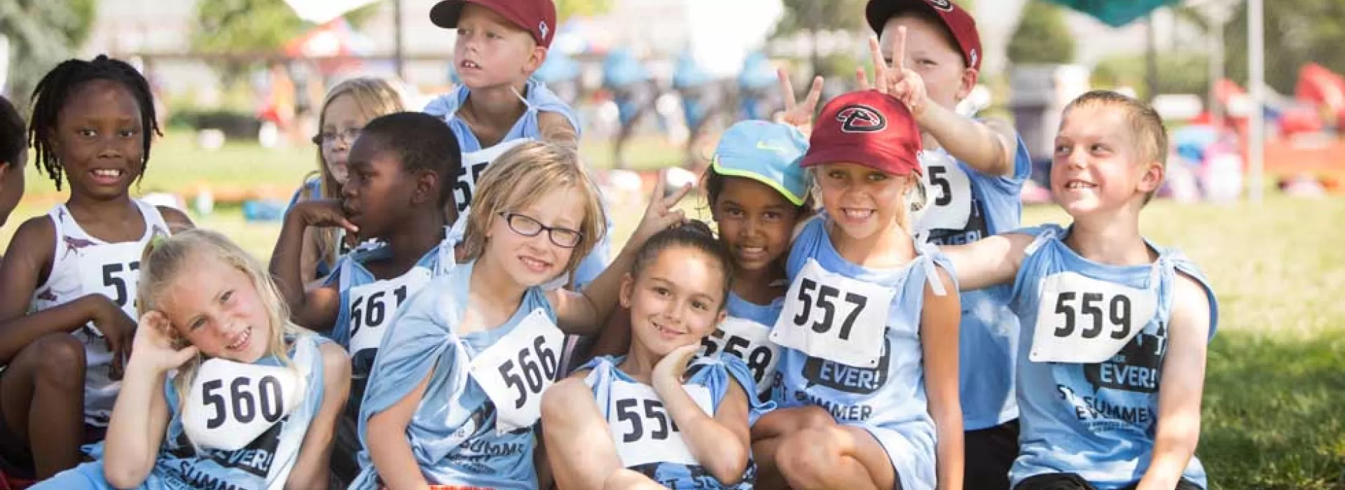 11 smiling kids in matching blue t-shirts at the YMCA's Day Camp Olympics at University of Dayton's Welcome Stadium