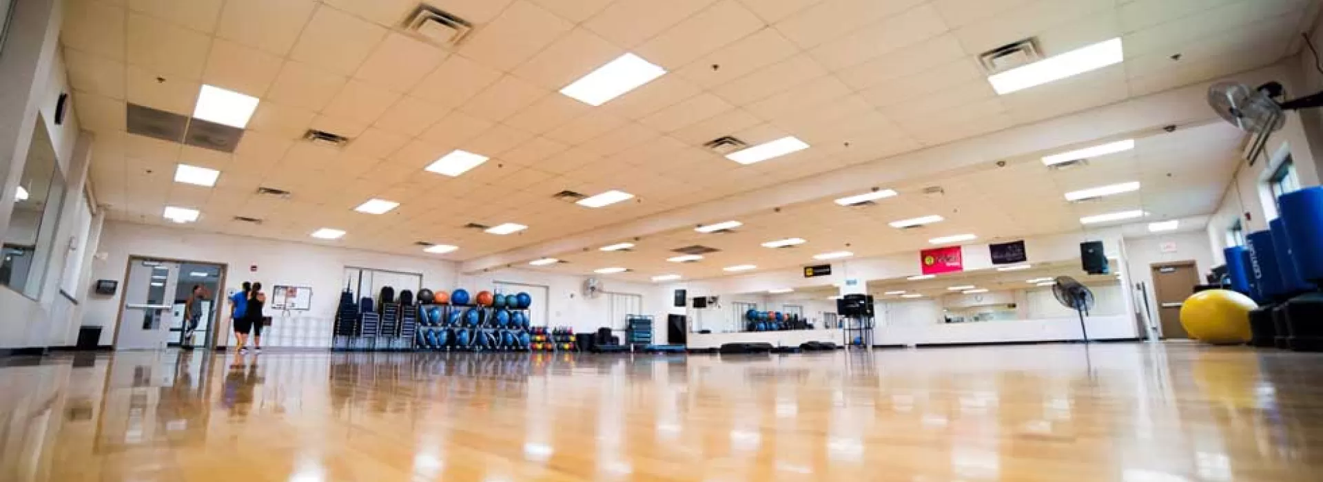Large, empty group exercise classroom at the Coffman YMCA taken from a low angle on the shining wooden floor