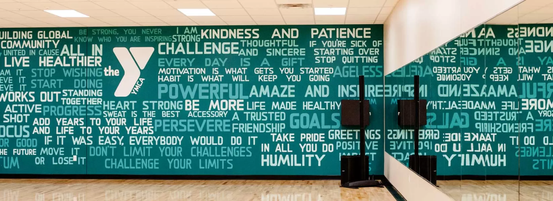 Group exercise room with a green wall with white, inspirational wording on the wall