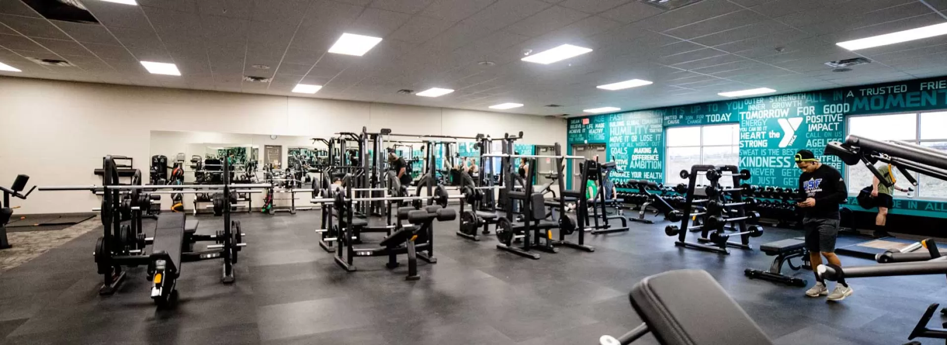 large fitness room at the Xenia YMCA with weight benches, barbells, and free weights