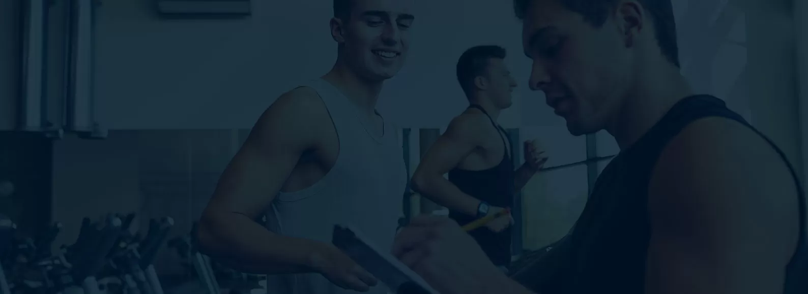 man running on treadmill as personal trainer assists and takes notes